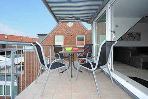 a patio with a table and chairs on a balcony at Nordseegartenpark Nordsee_Panorama in Bensersiel