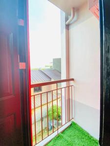 d'un balcon avec une porte rouge et de l'herbe verte. dans l'établissement Chael Staycation - Minimalist Modern 1-Bedroom, à Marilao