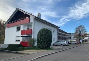un edificio blanco con ventanas rojas y coches aparcados en un aparcamiento en Apartment Kliniken, en Tübingen