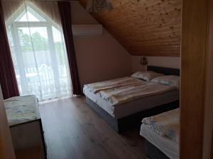 a bedroom with two beds and a large window at Alinka Apartmanház in Balatonlelle