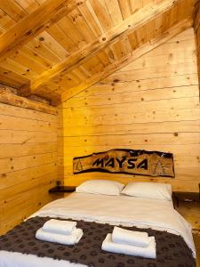 a bed in a log cabin with two towels on it at Maysa Suit Bungalov in Çamlıhemşin