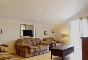sala de estar con 2 sofás y TV en Phoenix Lodge - Ramsgate KwaZulu Natal, en Margate