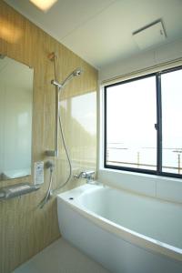 a bathroom with a bath tub and a window at Rainbow Village（レインボーヴィレッジ） in Mihama