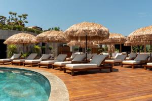 eine Terrasse mit Stühlen und einen Pool mit Strohschirmen in der Unterkunft Ala Suites and Villas Yalıkavak in Yalıkavak