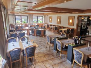 um restaurante com mesas, cadeiras e janelas em Hotel Grüner Baum mit Restaurant & Wellness em Beerfelden