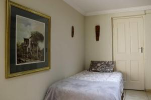 1 dormitorio con 1 cama y una foto en la pared en Phoenix Lodge - Ramsgate KwaZulu Natal, en Margate