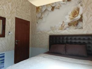 a bedroom with a bed and a wall with flowers at Unique Homestay 443 in Yogyakarta