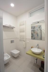 a white bathroom with two sinks and a toilet at Kris Luxury Apartments in Giardini Naxos