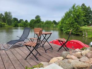 three chairs and a table on a dock next to a boat at Marcinówka in Gołdap