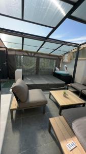 d'une terrasse avec des canapés, des tables et un toit. dans l'établissement Maison spa relaxing, à Le Fief-Sauvin