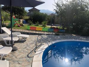 a swimming pool with chairs and an umbrella at Sunshine villa Dzhigurovo in Sandanski