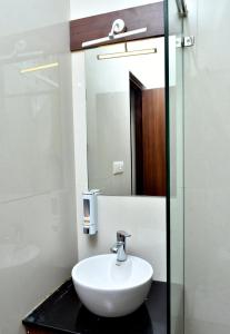 NāmakkalにあるKailash Residencyのバスルーム(白い洗面台、鏡付)