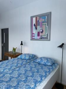 - une chambre dotée d'un lit bleu avec une photo sur le mur dans l'établissement Gisebo Vingård, à Huskvarna