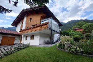 a house with a balcony and a yard at Alpenglück Montafon in Sankt Gallenkirch