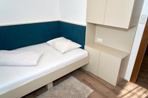 Habitación pequeña con cama y pared azul en Appartements am See, en Maria Wörth