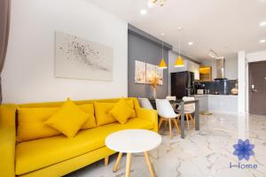 - un salon avec un canapé jaune et une table dans l'établissement iHome Furnished Apartments in Orchard Park View Building with Free Gym & Pool, Airport Pick-Up Service, à Hô-Chi-Minh-Ville