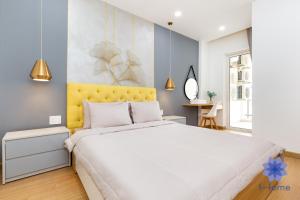 een slaapkamer met een wit bed en een geel hoofdeinde bij iHome Furnished Apartments in Orchard Park View Building with Free Gym & Pool, Airport Pick-Up Service in Ho Chi Minh-stad