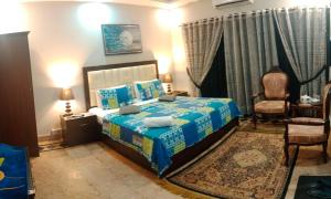 a bedroom with a bed with a blue comforter at Seaview Lodge Guest House in Karachi