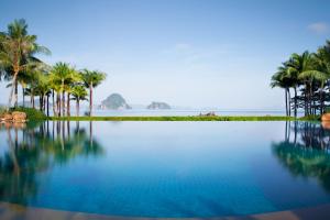 a pool of water with palm trees and the ocean at Phulay Bay, A Ritz-Carlton Reserve in Tab Kaek Beach