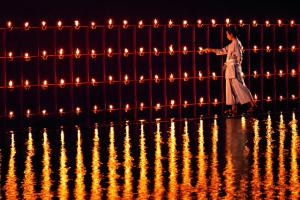 a woman standing next to a fence with lights at Phulay Bay, A Ritz-Carlton Reserve in Tab Kaek Beach