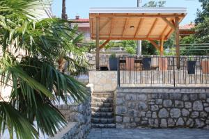 eine hölzerne Pergola und Treppe mit einer Steinmauer in der Unterkunft Apartment INES 2 with terrace, sea view, Jacuzzi, outdoor pool in Novi Vinodolski