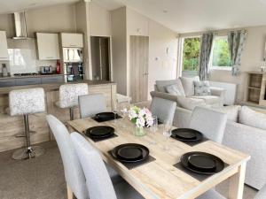 eine Küche und ein Wohnzimmer mit einem Holztisch und Stühlen in der Unterkunft The Retreat 22 - Hot Tub Lodge, pet friendly, WiFi - Golden Palm Resort - Meadow Lakes Caravan & Lodge Hire in Skegness
