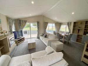 ein Wohnzimmer mit weißen Sofas und einem Fernseher in der Unterkunft The Retreat 22 - Hot Tub Lodge, pet friendly, WiFi - Golden Palm Resort - Meadow Lakes Caravan & Lodge Hire in Skegness