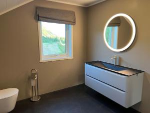 a bathroom with a sink and a toilet and a mirror at Leilighet i rolige omgivelser i Lofoten 