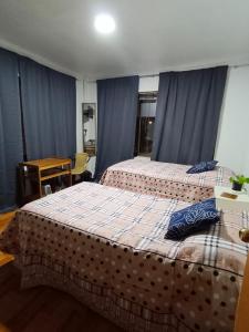 two beds in a room with blue curtains at Donde Gabriel in Chillán