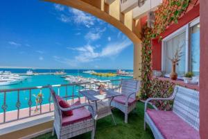Hurghada marina apartment sea view في الغردقة: شرفة مع طاولة وكراسي وإطلالة على الماء