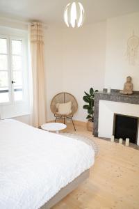 Dormitorio blanco con cama y chimenea en Sur mon chemin chambres d'hôtes, en Cahuzac-sur-Vère