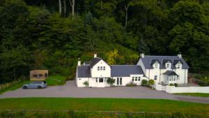 a white house with a car parked in the driveway at Craigneuk in Benderloch near Oban, stunning home with sea views in Oban