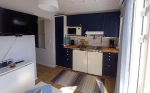 cocina con armarios azules y nevera blanca en Tofte Guesthouse nära hav, bad och Marstrand en Lycke