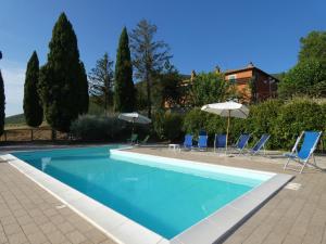 Montecchio的住宿－Scappo in Umbria, Casale Beatrice，一个带蓝色椅子和遮阳伞的游泳池
