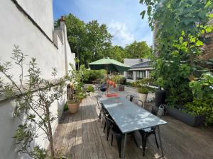 um deque de madeira com uma mesa e um guarda-chuva em Loft familial avec grand jardin verdoyant em Paris