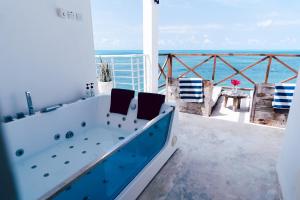 d'une baignoire installée au-dessus d'un balcon donnant sur l'océan. dans l'établissement Pili Pili Tropical Island, à Jambiani