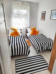twee bedden in een kleine kamer met gestreepte kussens bij Apartament Amber Comfort z prywatnym miejscem parkingowym in Kołobrzeg