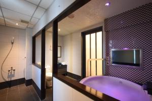 a bathroom with a large purple tub and a tv at Jin Spa Resort Hotel in Jinshan