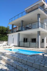 eine Villa mit einem Swimmingpool vor einem Haus in der Unterkunft Apartment INES 2 with terrace, sea view, Jacuzzi, outdoor pool in Novi Vinodolski