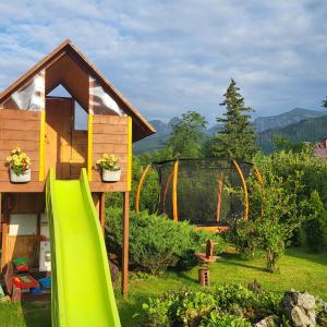 un patio trasero con un parque infantil con un tobogán verde en Topór Apartament widokowy z placem zabaw en Kościelisko