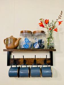 une étagère avec des bocaux en verre et un vase avec des fleurs dans l'établissement Yubara Hot Springs - Beautiful Riverside Hideaway, à Maniwa