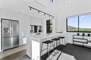een witte keuken met een aanrecht en krukken bij A Remarkable Stay - Jack's Point Holiday Home in Queenstown