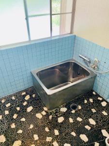 metalowa umywalka w łazience z podłogą wyłożoną kafelkami w obiekcie Yubara Hot Springs - Beautiful Riverside Hideaway w mieście Maniwa