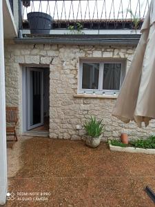a stone house with a patio and an umbrella at Le Petit Cosy in Saint-Front-la-Rivière