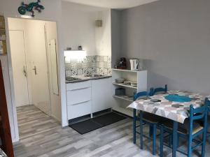 a kitchen with a table and blue chairs in a room at Studio duplex vue mer in Saint-Nic