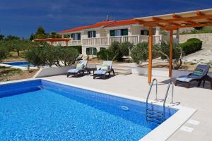 a pool with chairs and a house in the background at Holiday Homes Oliva in Bol