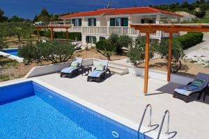 a patio with chairs and a pool in front of a house at Holiday Homes Oliva in Bol