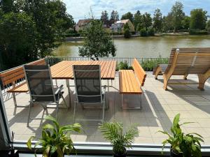 a deck with a wooden table and chairs and a river at Haus Seeblick in Allersberg