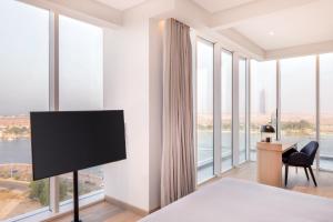 Habitación de hotel con TV y ventanas grandes. en Four Points by Sheraton Jeddah Corniche, en Yeda
