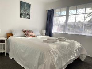 a bedroom with a white bed with towels on it at Ali Motel in Auckland